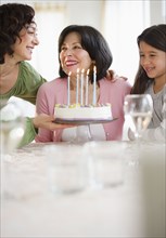 Mother and daughter giving birthday cake to grandmother