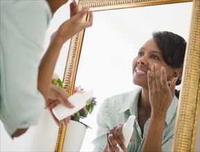 Black woman applying moisturizer