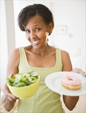 Black woman holding salad and donut