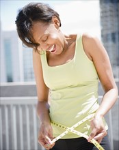 Black woman measuring her waistline