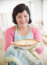 Hispanic woman holding out homemade pie