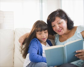 Hispanic mother and daughter reading a book