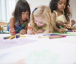 Children laying on floor coloring together