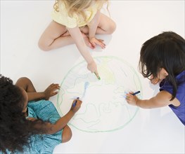 Girls sitting on floor drawing globe together