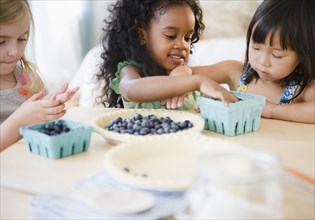 Girls putting blueberries into bowl together