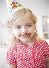 Caucasian girl at birthday party with chocolate on her face