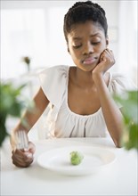 Frustrated Black woman looking at brussels sprout