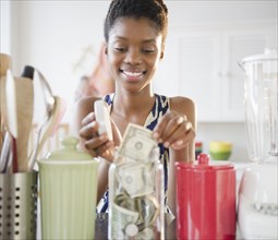 Black woman taking money out of jar