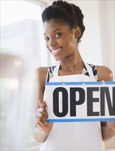 Black business owner holding open sign