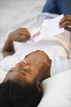 Black woman laying on bed reading Valentine's Day card