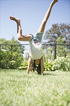 Hispanic girl doing cartwheels in grass
