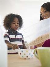 African American mother pouring cereal for son