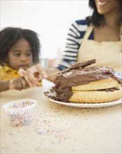 African American mother and son icing cake