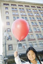 Korean girl holding red balloon outdoors