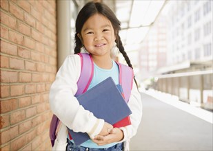 Korean girl holding books on sidewalk