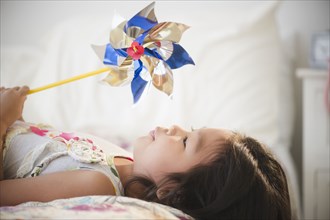 Korean girl laying on bed holding pinwheel