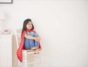 Korean girl in cape sitting on chair