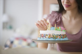 Mixed race woman preparing birthday cake