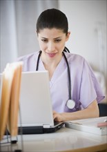 Mixed race nurse using laptop in hospital