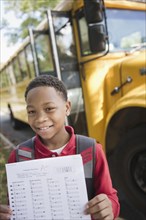 Mixed race boy holding test near school bus