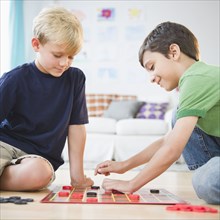 Boys sitting on floor playing checkers