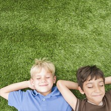 Boys with eyes closed laying in grass