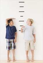 Boys measuring themselves against marks on wall