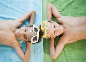 Boys laying on towels wearing swim goggles