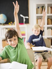 Boys in classroom raising hands