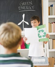 Hispanic boy reading recycling report in classroom