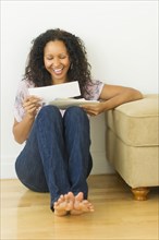 Hispanic woman sitting on floor looking at mail