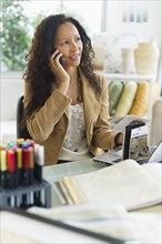 Hispanic businesswoman using cell phone at desk