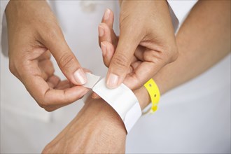 Nurse putting identification bracelet on patient in hospital