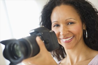 Hispanic woman taking photographs with camera