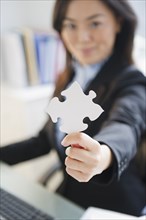 Japanese businesswoman holding puzzle piece