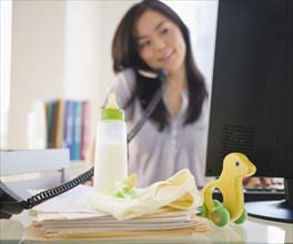 Japanese woman on phone with baby toys on desk