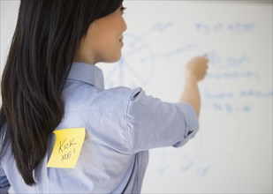 Japanese businesswoman with kick me note on back