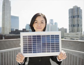 Japanese businesswoman holding solar panel outdoors