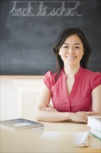 Japanese teacher sitting at desk in classroom