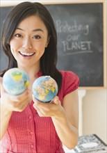Japanese teacher holding small globes in classroom