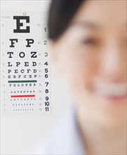 Japanese optometrist in front of eye chart