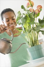 Black woman watering plant
