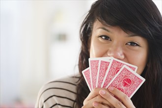 Pacific Islander woman covering her mouth with playing cards