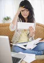Frustrated Pacific Islander woman paying bills