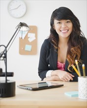 Pacific Islander businesswoman sitting at desk with digital tablet
