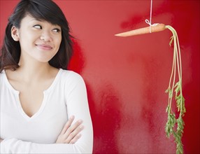 Pacific Islander woman looking at a carrot on a string