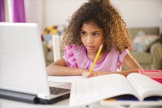 Mixed race girl doing homework with laptop