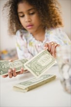 Mixed race girl counting dollar bills