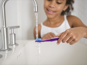 Mixed race girl brushing her teeth
