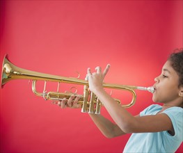 Mixed race girl playing trumpet